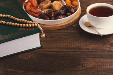 Kurutulmuş meyve tabağı, ahşap tespih, Kur 'an, kahverengi ahşap arka planda çay, iftar konsepti, Ramazan, Müslüman bayramı.