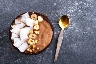 Hindistan cevizli çikolatalı smoothie, hindistan cevizi kabında fındık, smoothie kasesi konsepti, gri arka planda tatlı kaşığı, kopyalama alanı