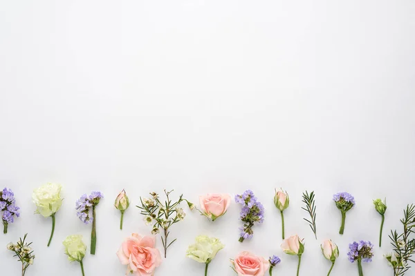 flower composition of rose buds, eustoma, limonium inflorescences on white background, copy space, space for text, top view, flat lay