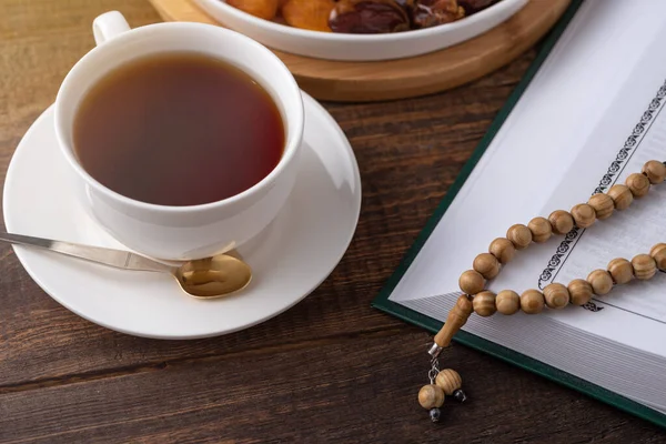 ラマダーン月 コーランでの祈りのビーズ お茶のカップ 茶色の木製の背景にドライフルーツのプレート Iftarコンセプト — ストック写真