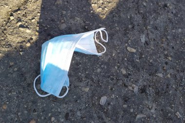 Asfaltta mavi tıbbi maske, karantinanın sonu, koronavirüs salgını konsepti