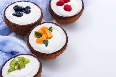 Hindistan cevizi kaselerinde dondurma, beyaz arka planda böğürtlen, meyve suyu kasesi konsepti, moda tatlı, fotokopi alanı