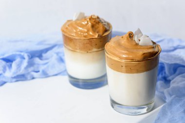 Beyaz arka planda hindistan cevizi taneli, mavi gazlı ve Kore kahvesi kavramlı modaya uygun dalgona kahvesi.