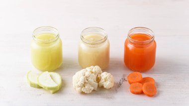 Doğal sebze mamaları cam kavanozlarda kabak, karnabahar, beyaz arka planda havuç, ev yapımı organik yiyecekler.