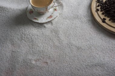 Bir fincan kahve ve kahve üzerinde mavi bir arka plan üzerinde beyaz kum taneleri