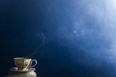 Bir fincan kahve ve kahve üzerinde mavi bir arka plan üzerinde beyaz kum taneleri