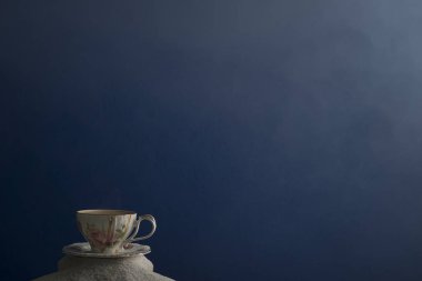 Bir fincan kahve ve kahve üzerinde mavi bir arka plan üzerinde beyaz kum taneleri