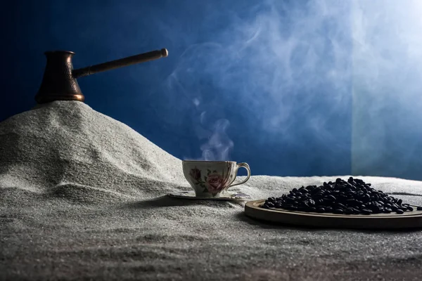 Bir fincan kahve ve kahve üzerinde mavi bir arka plan üzerinde beyaz kum taneleri