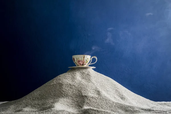 Bir fincan kahve ve kahve üzerinde mavi bir arka plan üzerinde beyaz kum taneleri