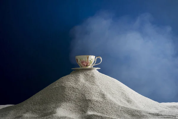 Bir fincan kahve ve kahve üzerinde mavi bir arka plan üzerinde beyaz kum taneleri