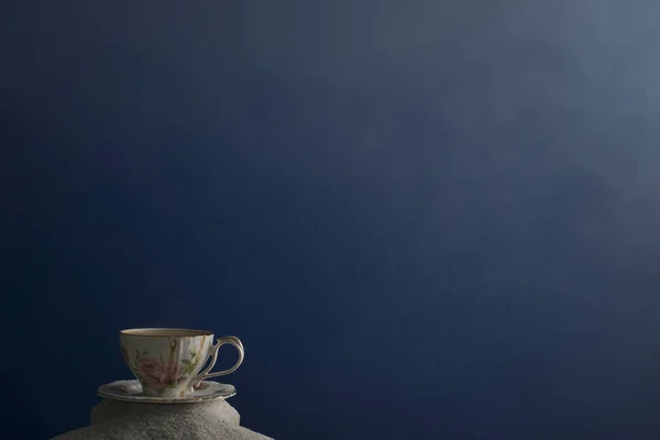 Bir fincan kahve ve kahve üzerinde mavi bir arka plan üzerinde beyaz kum taneleri