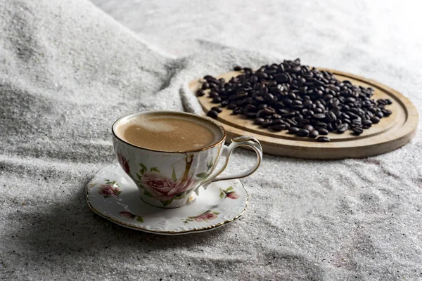 Bir fincan kahve ve kahve üzerinde mavi bir arka plan üzerinde beyaz kum taneleri