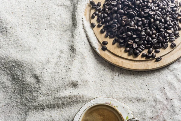 Bir fincan kahve ve kahve üzerinde mavi bir arka plan üzerinde beyaz kum taneleri