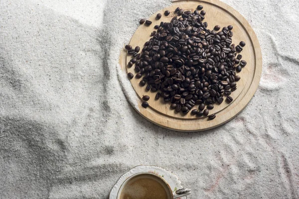 Bir fincan kahve ve kahve üzerinde mavi bir arka plan üzerinde beyaz kum taneleri