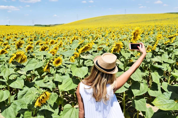 Bir kızla selfie alarak büyük bir ayçiçeği çiftliğinde hasır şapka