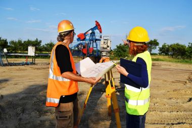 İki geodets anda bir petrol kuyusu üzerinde