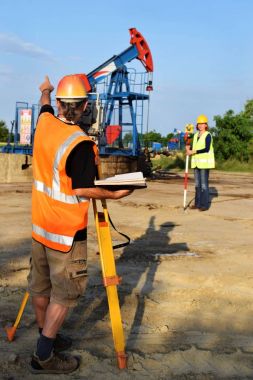 İki geodets anda bir petrol kuyusu üzerinde