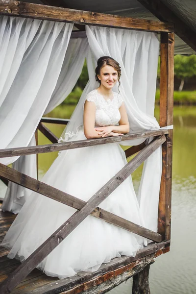 Noiva posando no cais no lago — Fotografia de Stock