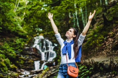 Mutlu genç kadın arka planda şelale ile doğa eller Yayilim