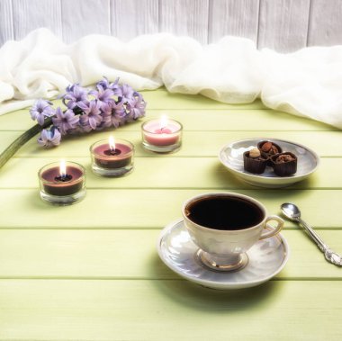 Fincan sade kahve, mumlar ve çiçekler