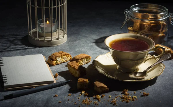 Cup of tea , almond cookies and notebook.