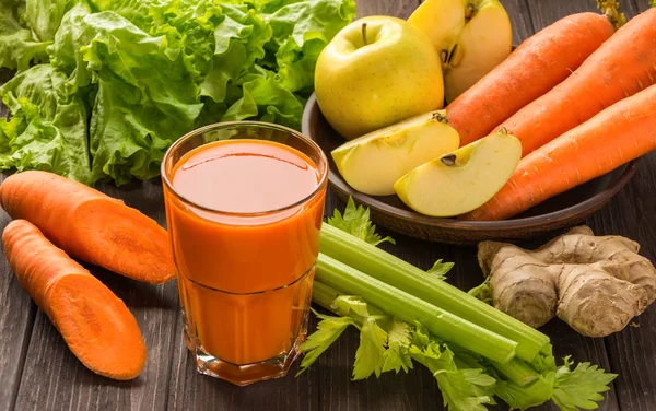 Gulerod og æblejuice med grøntsager på mørk træbaggrund - Stock-foto