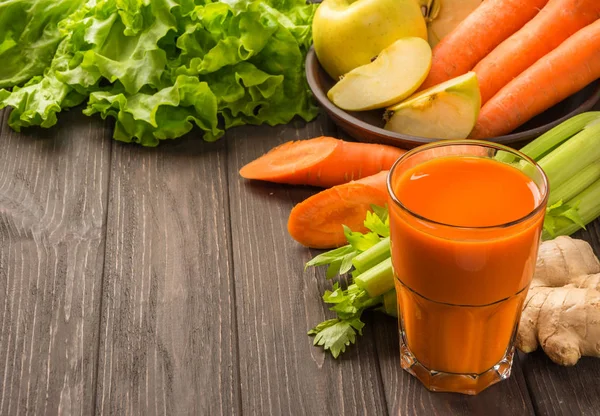 Koyu ahşap zemin üzerine sebzeli havuç ve elma suyu