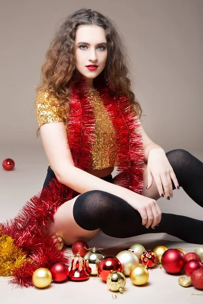 クリスマスのボールと赤のクリスマスのおもちゃでゴールドのドレスで美しい少女 — ストック写真