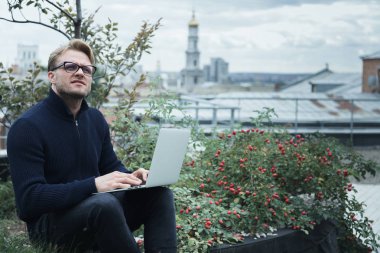 Çatıda çalışan yakışıklı genç işadamı