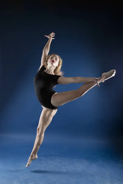 girl dancer in a jump and a beautiful pose on a blue background