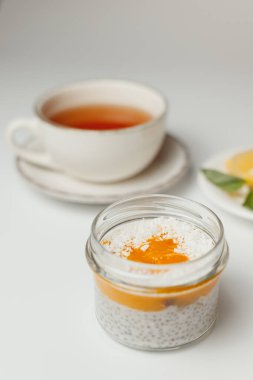 Şeftalili ve hindistan cevizli chia pudingi, beyaz arka planda limonlu çay.