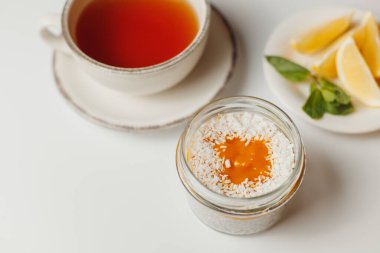 Şeftalili ve hindistan cevizli chia pudingi, beyaz arka planda limonlu çay.