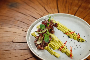 Siyah havyarlı ton balığı tartartarı, avokado mus, kırmızı biber, susam tohumu, roka, pazı ve ahşap arka planda mikroyeşil.