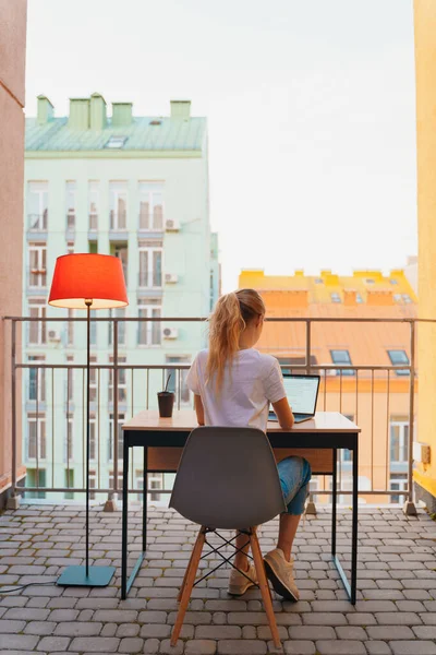 Young tired woman using laptop on terrace