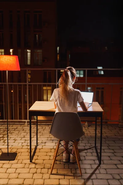 Genç yorgun kadın terasta dizüstü bilgisayar kullanıyor.