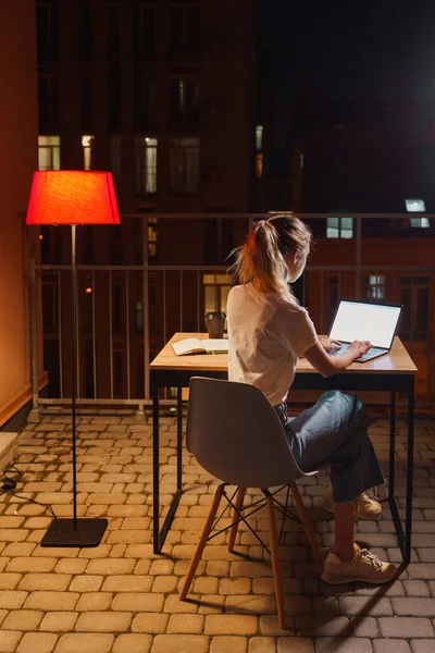 Genç yorgun kadın terasta dizüstü bilgisayar kullanıyor.