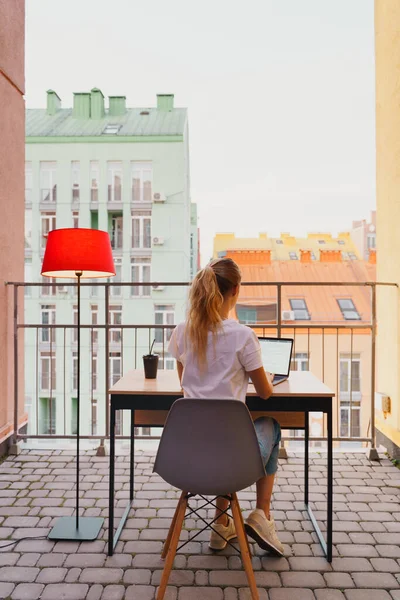 Genç yorgun kadın terasta dizüstü bilgisayar kullanıyor.