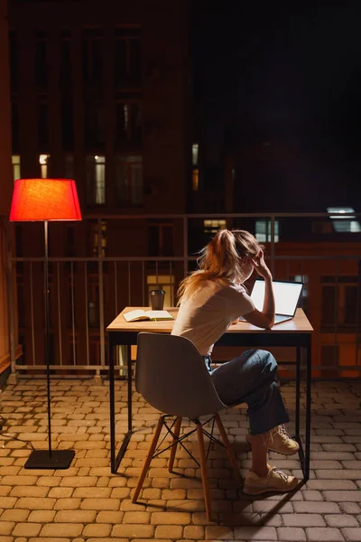 Young tired woman using laptop on terrace