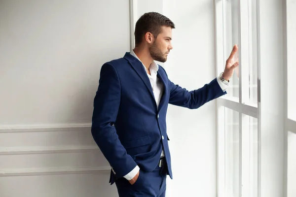 young man wearing jacket posing by window