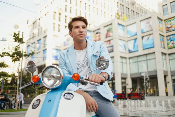 城市里穿着蓝色衣服的年轻人骑摩托车摆姿势 — 图库照片