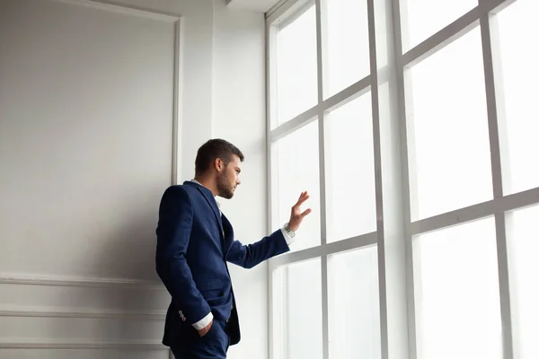 young man wearing jacket posing by window