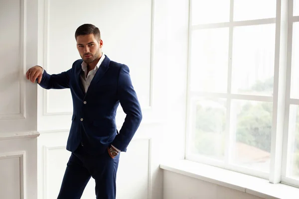 young man wearing jacket posing by window