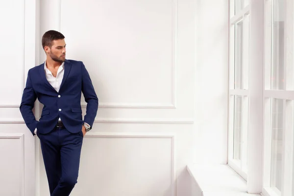 young man wearing jacket posing by window