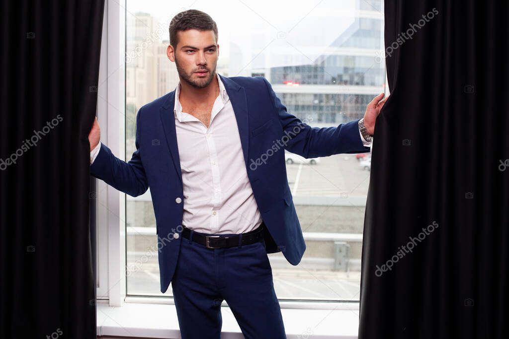 young man wearing jacket posing by window 