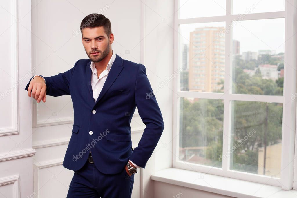 young man wearing jacket posing by window 