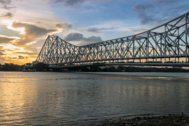 Gün batımında Hooghly nehrinde Howrah Köprüsü. Howrah Köprüsü, Batı Bengal, Hindistan 'daki Hooghly Nehri üzerinde askıya alınmış bir köprüdür..