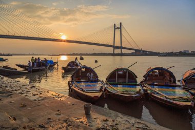 Günbatımında Princep Ghat Hooghly nehrinde, dizilmiş zevk tekne sürmek için kullanılan ahşap ülke tekneler. Fon, Vidyasagar tertibat (köprü).