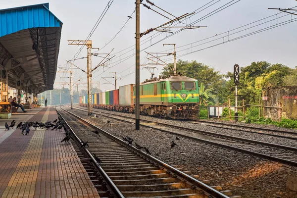 Tren de mercancías de los ferrocarriles indios que cruzan una estación de ferrocarril desierta en Calcuta, India . — Foto de Stock
