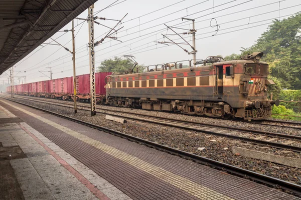 Tren de mercancías de los ferrocarriles indios cruza una plataforma vacía en una nebulosa mañana de invierno . — Foto de Stock