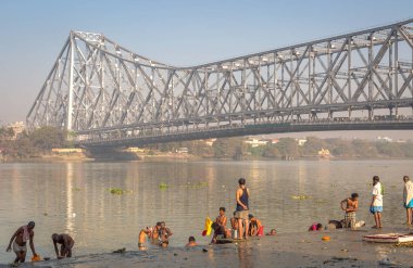 İnsanlar Hooghly Nehri bankalar, fon, tarihi Howrah bridge ile banyo.